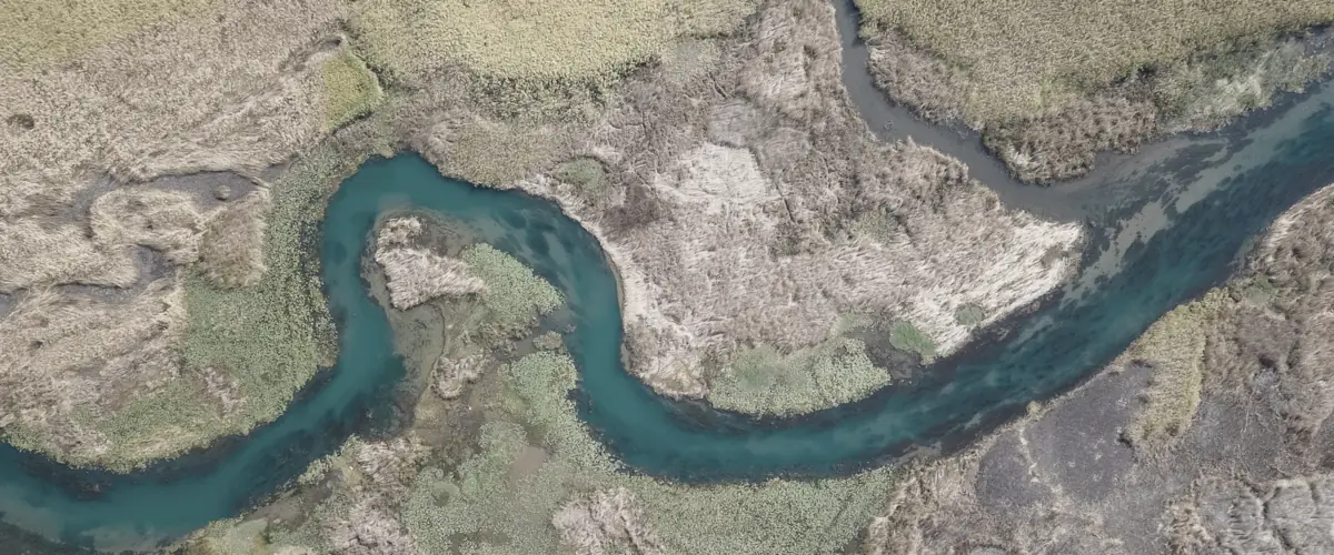 Aerial view of a river winding steadily through open marshland